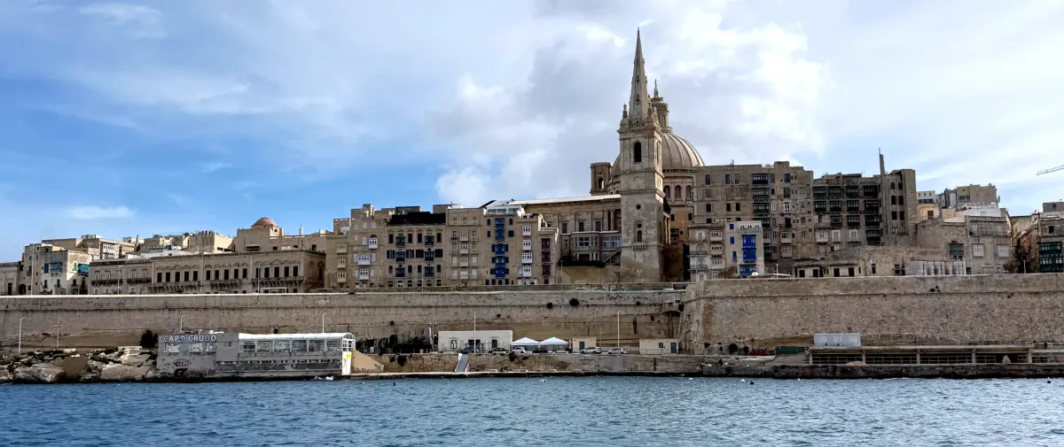 Fortified stone city and church spire along a Malta waterfront