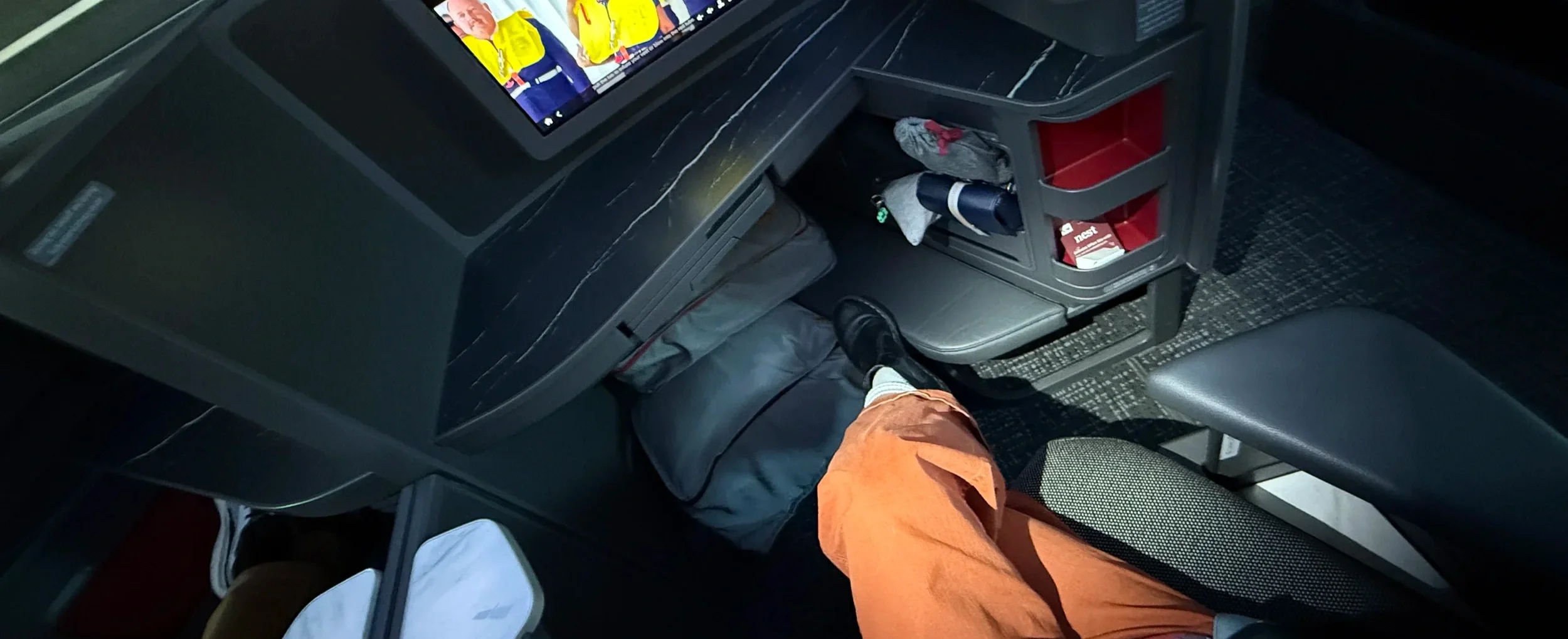 Passenger view of a business-class seat, screen, and footwell