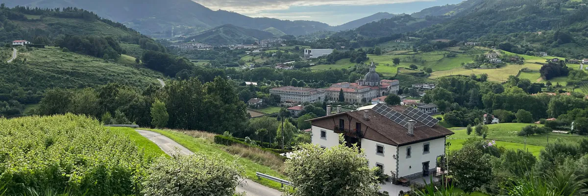 Green hills, a white house, and a distant domed complex