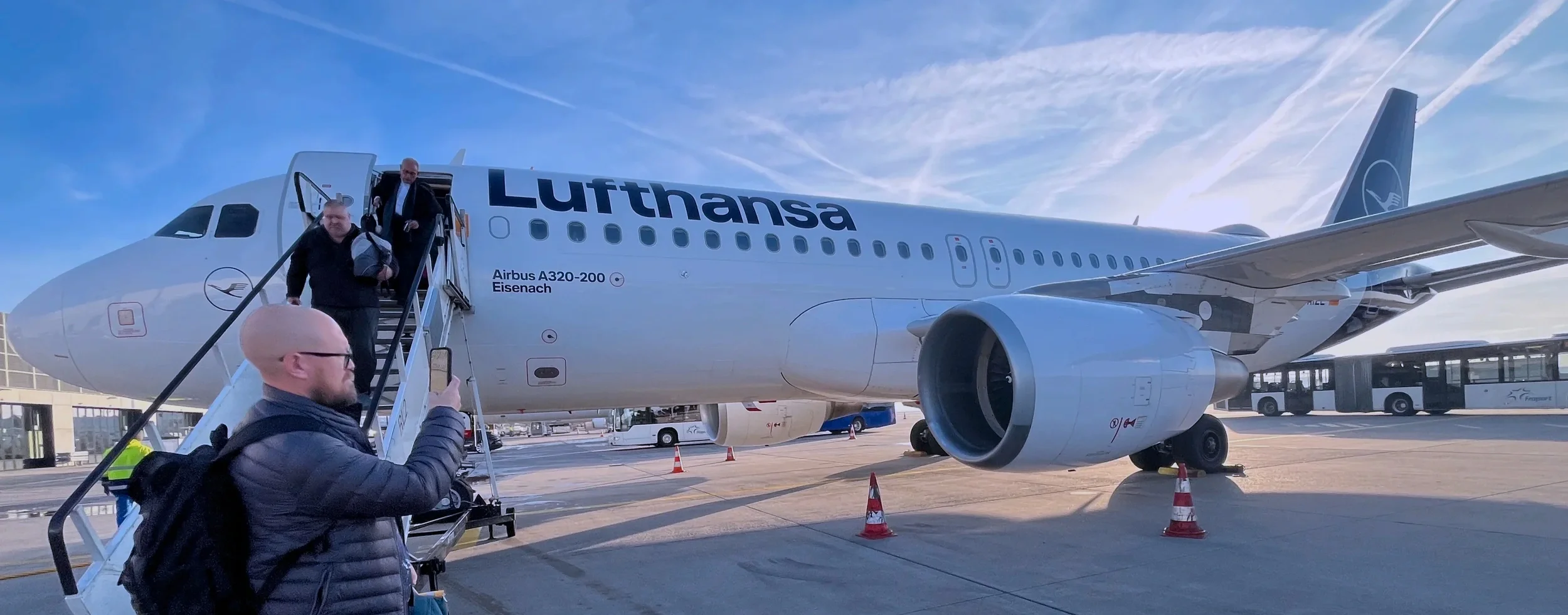 Travelers boarding a Lufthansa Airbus A320 by mobile stairs