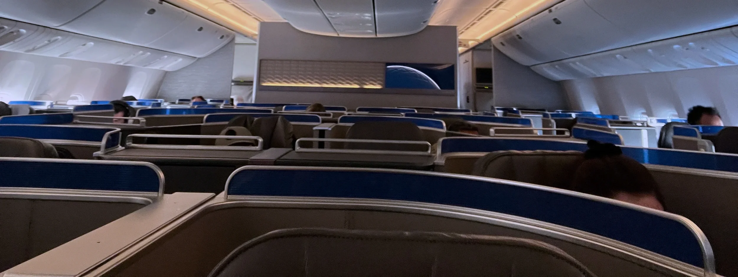 Business class cabin with blue privacy dividers and seated passengers