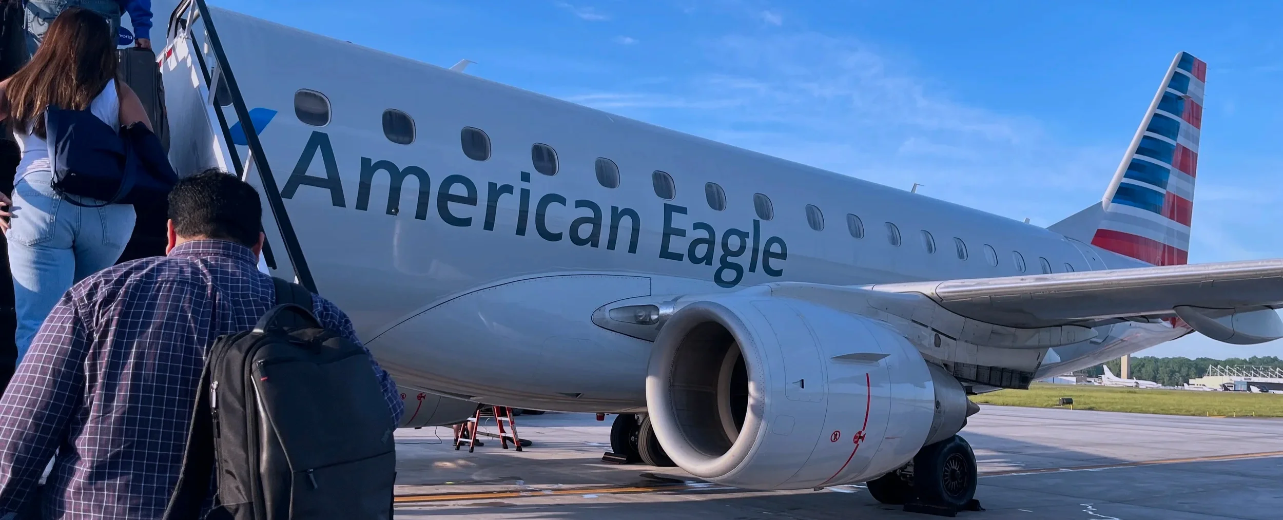 Passengers climbing stairs to board an American Eagle jet